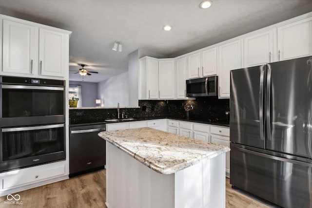 kitchen with sink, backsplash, stainless steel appliances, white cabinets, and a kitchen island