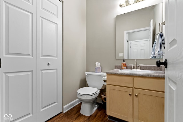 2231 Colfax Ln, Indianapolis, IN 46260 - bathroom featuring wood finished floors, toilet, vanity, baseboards, and a closet