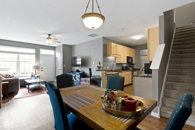 2231 Colfax Ln, Indianapolis, IN 46260 - dining space featuring light wood-style floors, stairway, ceiling fan, and baseboards