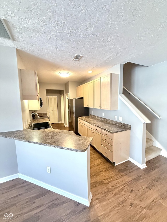 2231 Colfax Ln, Indianapolis, IN 46260 - kitchen with freestanding refrigerator, a peninsula, dark wood-style floors, a textured ceiling, and stove