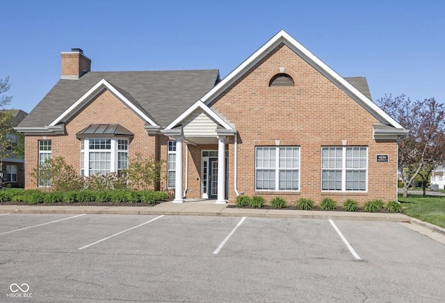 2231 Colfax Ln, Indianapolis, IN 46260 - view of front facade with brick siding, uncovered parking, and a chimney