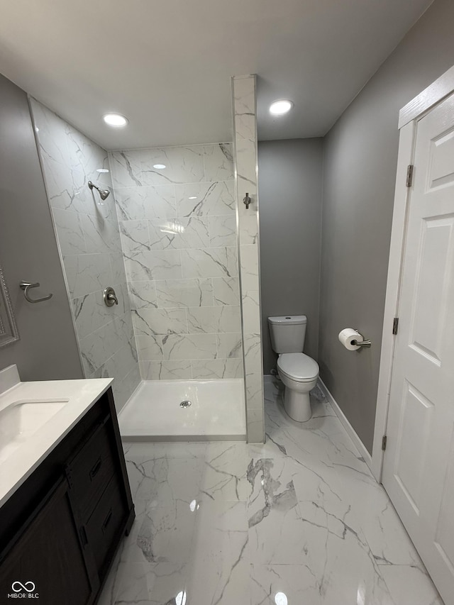 bathroom featuring vanity, a tile shower, and toilet