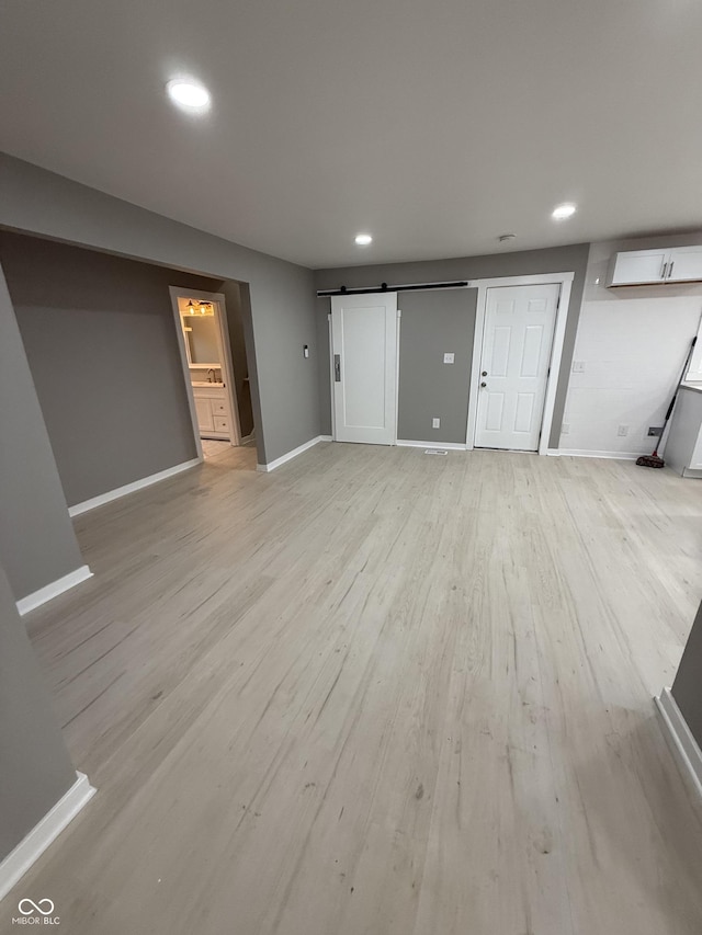 unfurnished living room featuring a barn door and light wood-type flooring