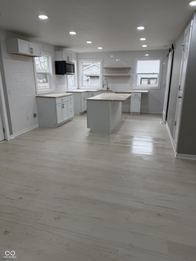 kitchen featuring white cabinetry, sink, a center island, a barn door, and light hardwood / wood-style flooring