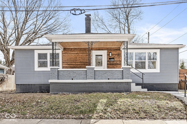 view of front facade featuring a porch, crawl space, fence, and a chimney