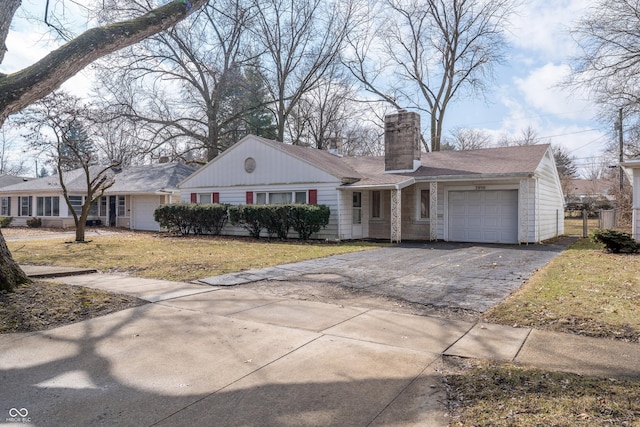 ranch-style home with a garage, driveway, a chimney, and a front lawn