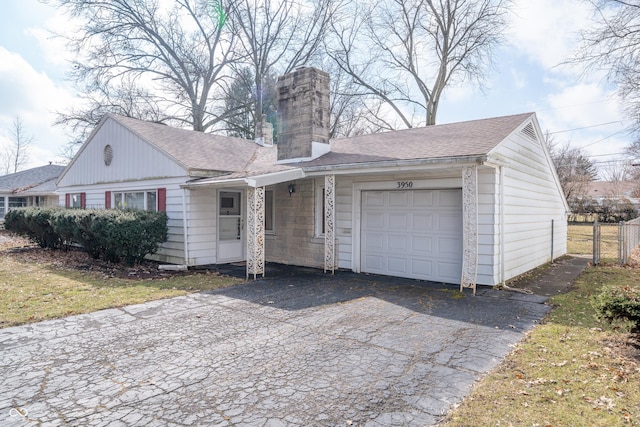 view of front facade featuring a garage, a shingled roof, a chimney, and fence