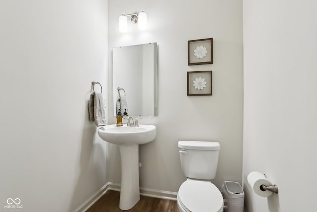 bathroom with hardwood / wood-style flooring, toilet, and sink