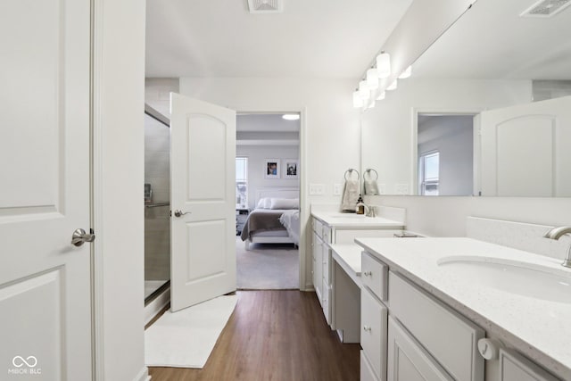 bathroom featuring wood-type flooring, a shower with shower door, and vanity