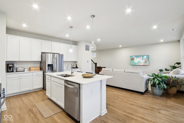 kitchen featuring sink, dishwasher, a kitchen island with sink, white cabinetry, and decorative light fixtures