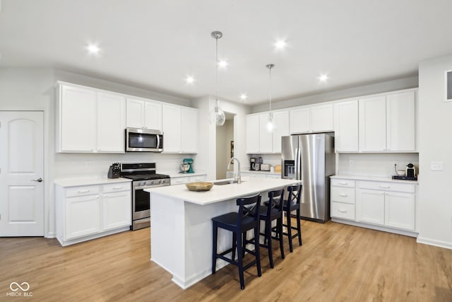 kitchen with sink, pendant lighting, stainless steel appliances, a kitchen island with sink, and white cabinets