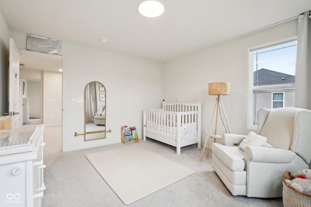 bedroom featuring a crib and light colored carpet