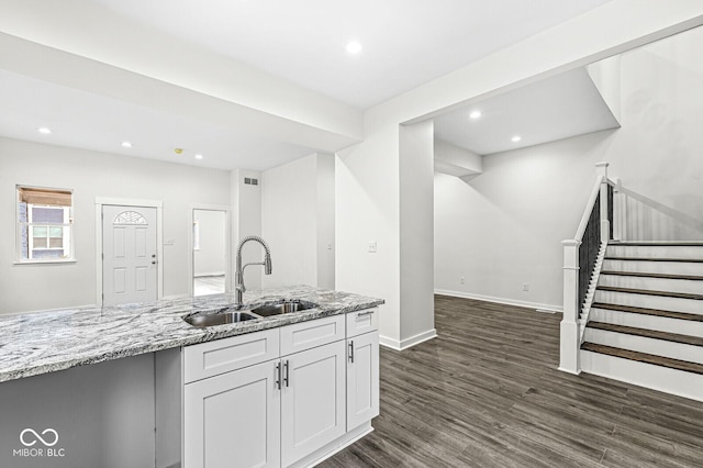 kitchen with white cabinetry, dark hardwood / wood-style floors, light stone countertops, and sink