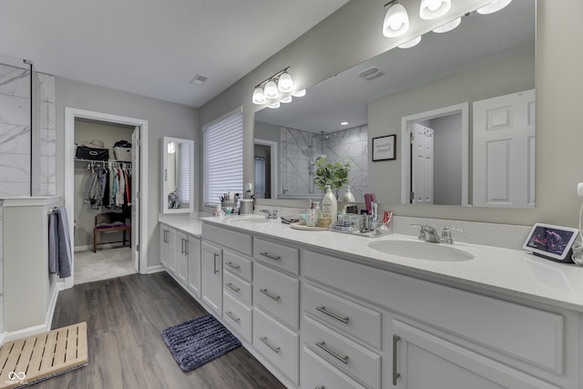 bathroom with vanity, wood-type flooring, and tiled shower