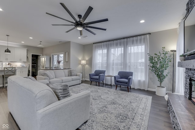 living room featuring a stone fireplace, ceiling fan, and light hardwood / wood-style flooring