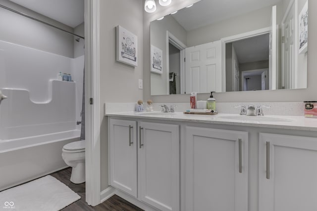 full bathroom with hardwood / wood-style flooring, bathing tub / shower combination, vanity, and toilet