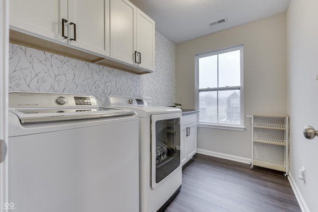 clothes washing area featuring cabinets, washer and dryer, dark wood-type flooring, and a textured ceiling