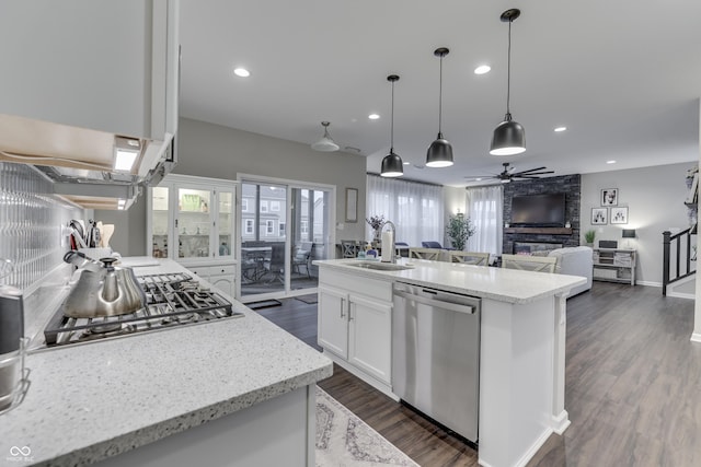 kitchen featuring an island with sink, sink, white cabinets, light stone counters, and stainless steel appliances