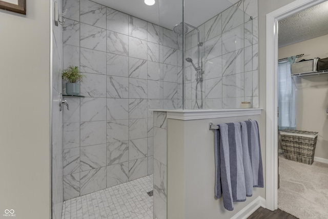 bathroom with a tile shower and a textured ceiling