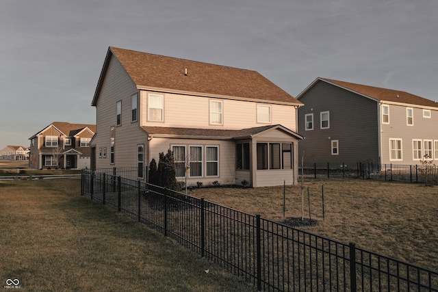 back of property with a lawn and a sunroom