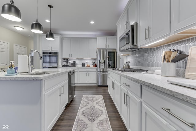 kitchen with appliances with stainless steel finishes, decorative light fixtures, white cabinetry, sink, and light stone countertops