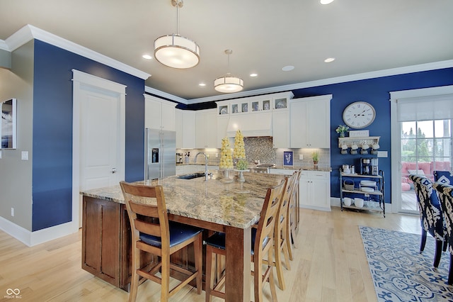 14445 Gainesway Cir, Fishers, IN 46040 - kitchen with high end fridge, ornamental molding, decorative backsplash, light wood-style flooring, and a breakfast bar area
