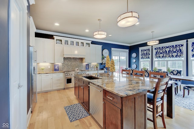 14445 Gainesway Cir, Fishers, IN 46040 - kitchen with appliances with stainless steel finishes, crown molding, a breakfast bar area, light wood finished floors, and backsplash