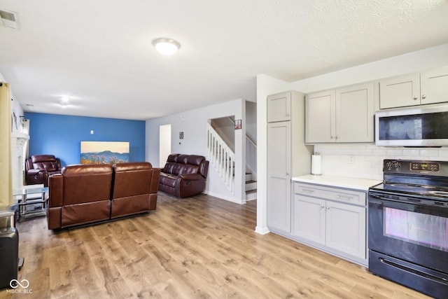 kitchen with tasteful backsplash, light hardwood / wood-style floors, and black electric range