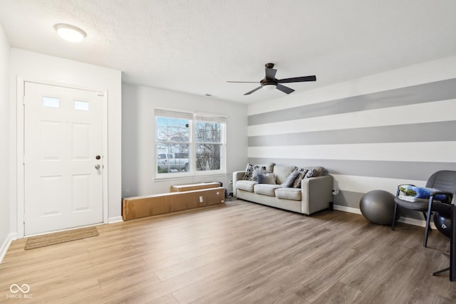 living room featuring wood-type flooring, ceiling fan, and a textured ceiling