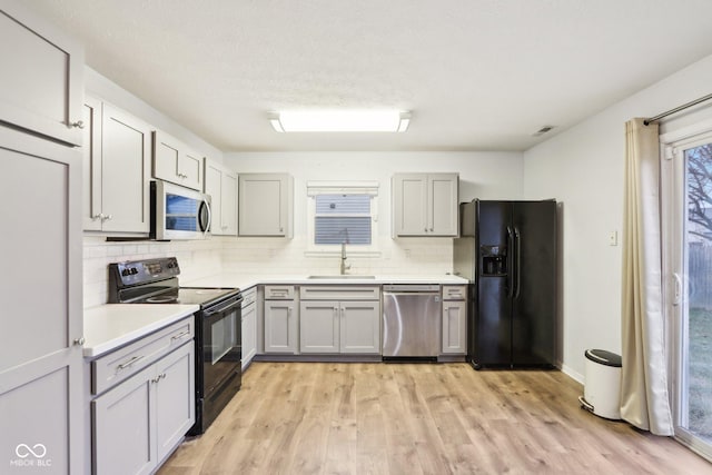 kitchen with gray cabinets, sink, decorative backsplash, and black appliances