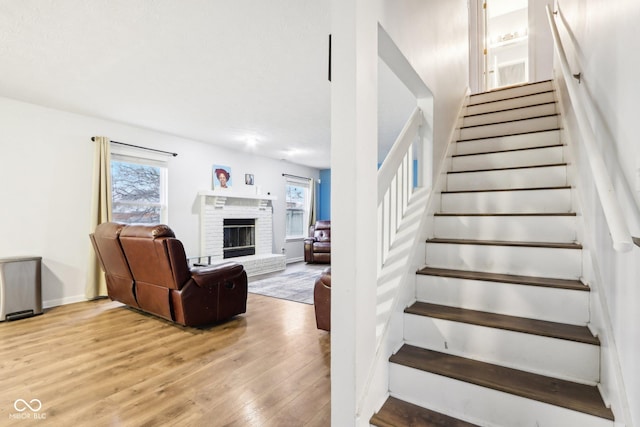 staircase featuring a brick fireplace, hardwood / wood-style flooring, and a wealth of natural light