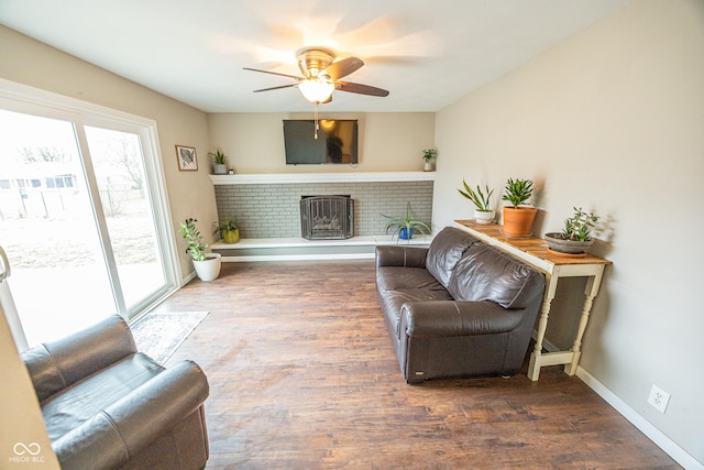 living room featuring ceiling fan, a fireplace, and dark hardwood / wood-style flooring