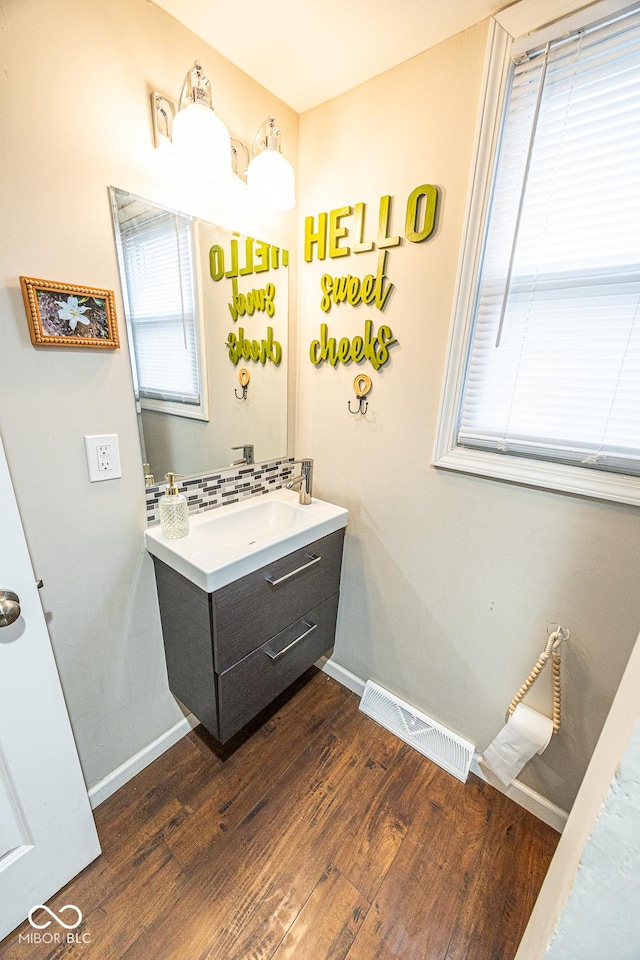 bathroom with vanity, hardwood / wood-style flooring, and tasteful backsplash