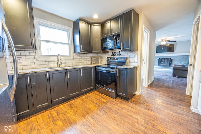 kitchen featuring stainless steel electric stove, light stone countertops, sink, and light hardwood / wood-style floors