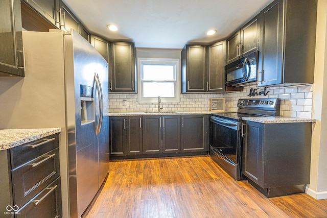 kitchen with sink, light wood-type flooring, stainless steel appliances, and light stone countertops