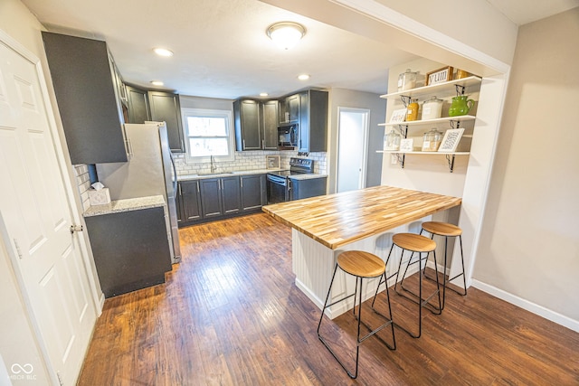 kitchen featuring dark hardwood / wood-style floors, sink, backsplash, a kitchen bar, and black appliances