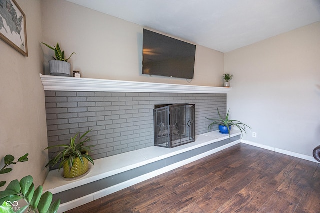 unfurnished living room with wood-type flooring and a brick fireplace