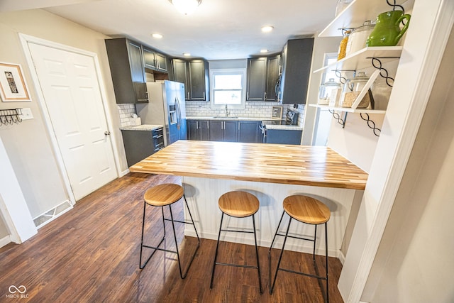 kitchen with butcher block counters, dark hardwood / wood-style flooring, a kitchen breakfast bar, and electric stove