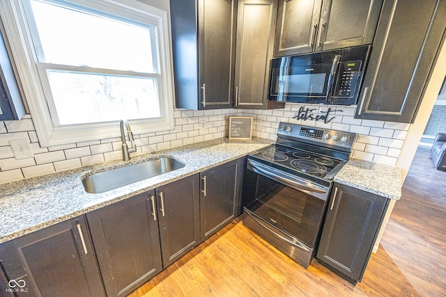 kitchen featuring stainless steel electric stove, sink, light stone counters, and light wood-type flooring