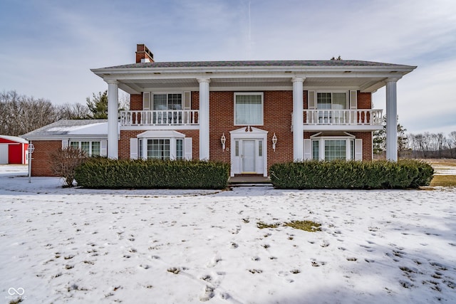 greek revival house featuring brick siding and a chimney