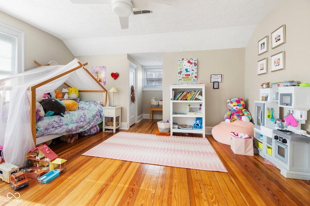 bedroom featuring lofted ceiling, hardwood / wood-style floors, a textured ceiling, and ceiling fan