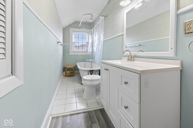 bathroom featuring vanity, lofted ceiling, tile patterned floors, and toilet