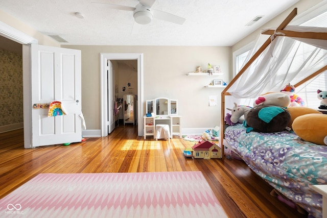 bedroom featuring ceiling fan, light hardwood / wood-style floors, and a textured ceiling