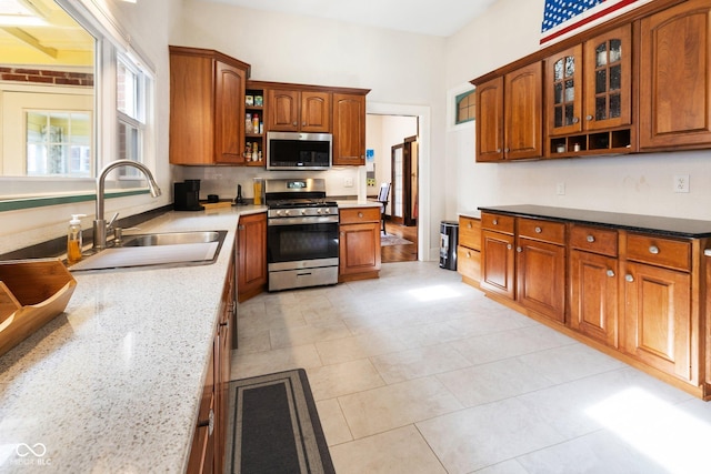 kitchen featuring appliances with stainless steel finishes, sink, light tile patterned floors, and light stone counters