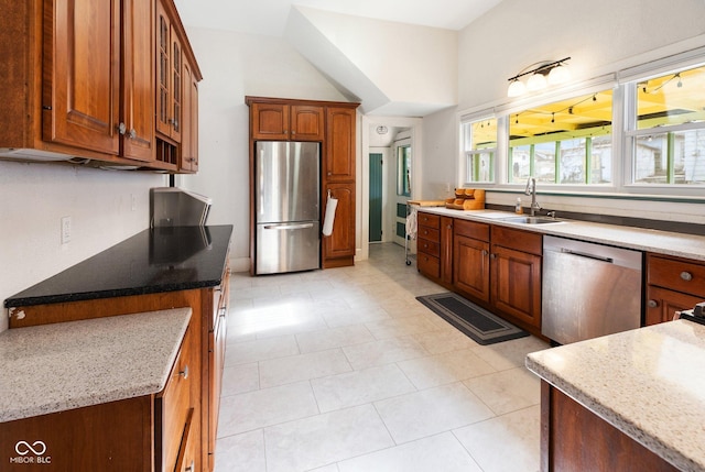 kitchen with stainless steel appliances, light stone countertops, and sink