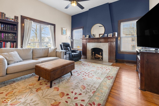 living room with ceiling fan, a fireplace, and light hardwood / wood-style floors