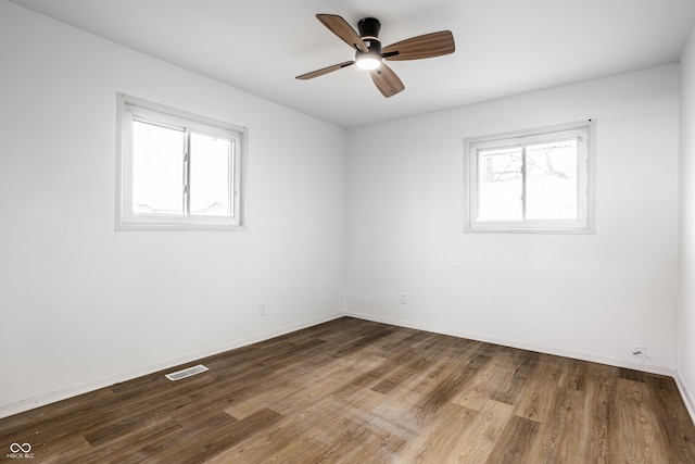 empty room featuring ceiling fan, wood-type flooring, and a healthy amount of sunlight