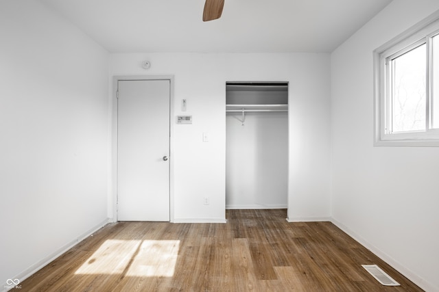 unfurnished bedroom featuring wood-type flooring, ceiling fan, and a closet