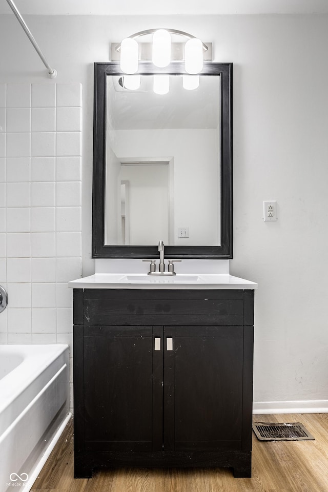 bathroom with washtub / shower combination, wood-type flooring, and vanity