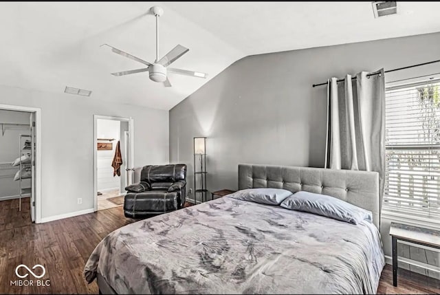 bedroom with lofted ceiling, dark hardwood / wood-style flooring, a walk in closet, ceiling fan, and ensuite bath